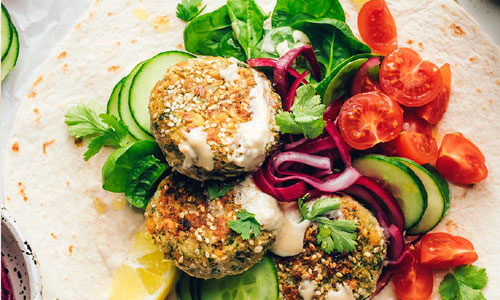 A freshly wrapped crispy Falafel Wrap Classic shown sliced in half